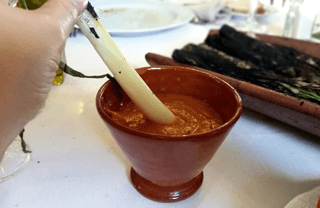 Dipping a Catalan Spring onion on sauce