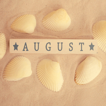 Word "August" written in a piece of wood in a Barcelona beach
